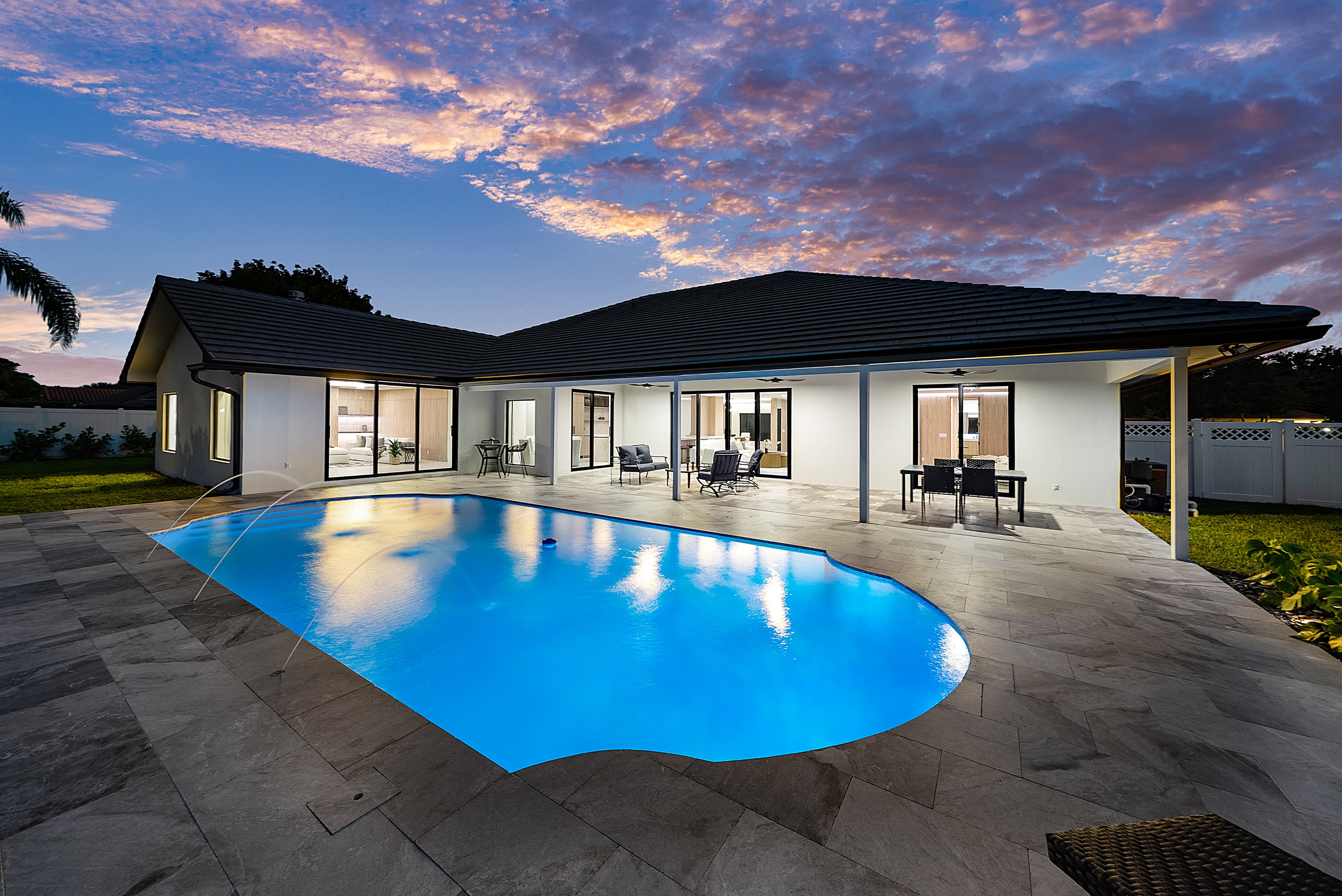 Pool home with impact sliding glass doors at twilight