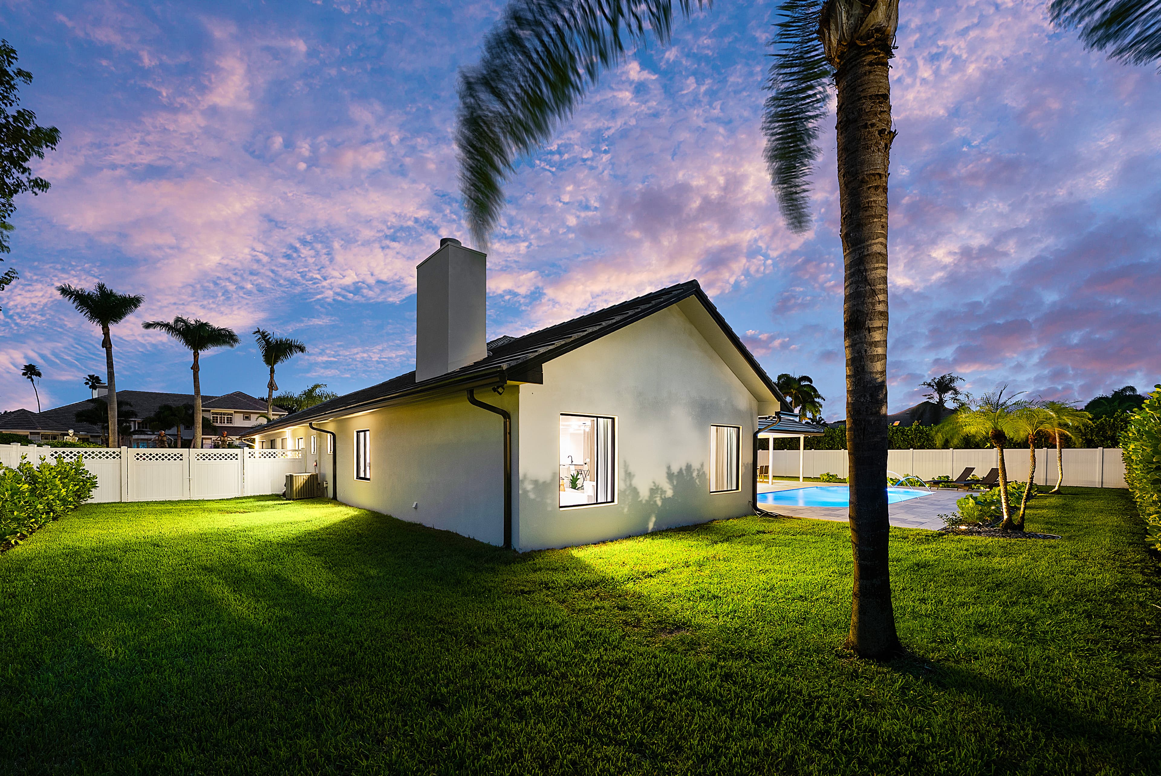 Home rear elevation at twilight with impact windows and pool
