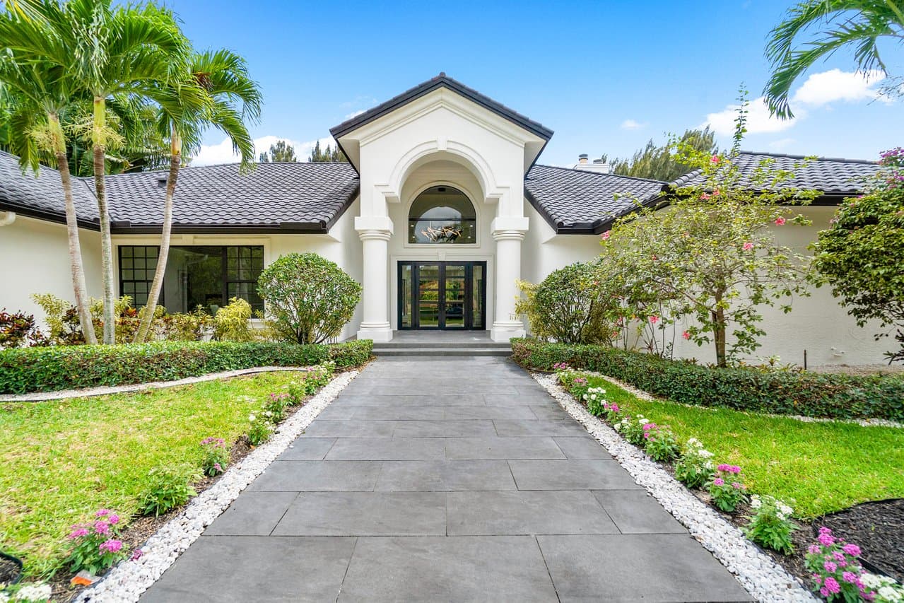 Estate home with arched entry and black impact French doors